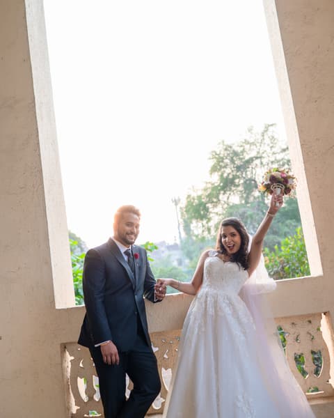 Bride raising her bouquet beside the groom